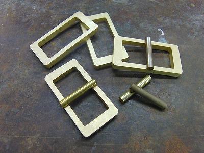 真鍮製で職人手作り、オリジナルピンバックルの特注オーダー Original Brass Metal Buckle   北海道にて、ブランド、モノ作りを展開なされているお客様より、使い込むほどに艶やかさ、味わいを楽しめる真ちゅう素材の、全て手作りのオリジナルバックルを作成していきました。まず、真ちゅうを削りだし、それぞれのパーツを取り揃えていきます。  真ちゅうを削り出して、商品を成形していく”挽きモノ”という技術を使用していきます。  