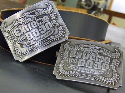 金具職人手作り、ブランドロゴ入り、オリジナルデザインのベルトバックルのオーダーメイド  Original Belt Buckle fittings    メタルハウスでは、オリジナルのボタン、ホック、チャーム、ネームプレートと、さまざまなオリジナル金具の依頼を受けます が、最近では、会社の社員用に、結婚式の記念品として、またセールスプロモーションの販促品としてなど、沢山の業種のお客様向けにオリジナル金具を作らせ ていただいています。     今回は建設業を営んでいらっしゃるお客さまから、社員用のオリジナルのバックル金具と、ベルトの革部分の縫製（完成品）と、イベント会社さま向けにＤＯＪＹＯ＝道場用のオリジナルバックルを作りました。