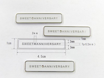 光沢ニッケル仕上げに、SWEET○ANNIVERSARYのロゴが中央に彫刻されているのが分かりますか？ロゴの中間の○の中にはスワロフスキーのラインストーンも取り付けられ、最後に純白のエポキシ樹脂の仕上げとなっております。