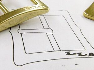 少ロットということで、真ちゅうの板材をご要望の指示通りに削りだし、ブランドのロゴを一つ一つ彫刻し、作成していきました。生地の製作から、加工、磨き、メッキ、全ての工程を熟練の職人さん職人が１つひとつ丁寧に商品と向かい合いながら大切に作り上げていきました。